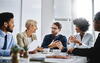 a group of people sitting at a table and laughing during a meeting 